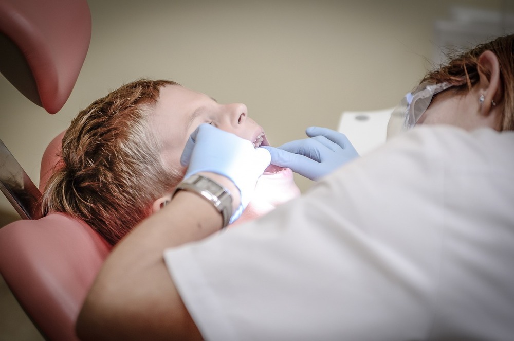 A dentist looks into a child's mouth
