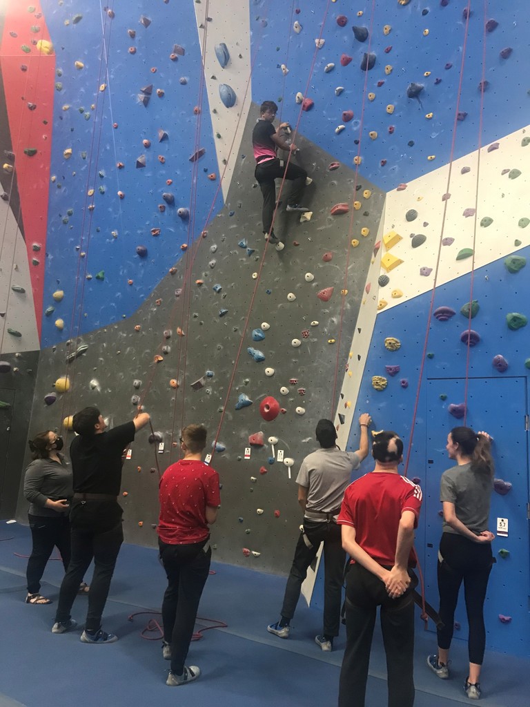 Students watch a climber on a rock wall