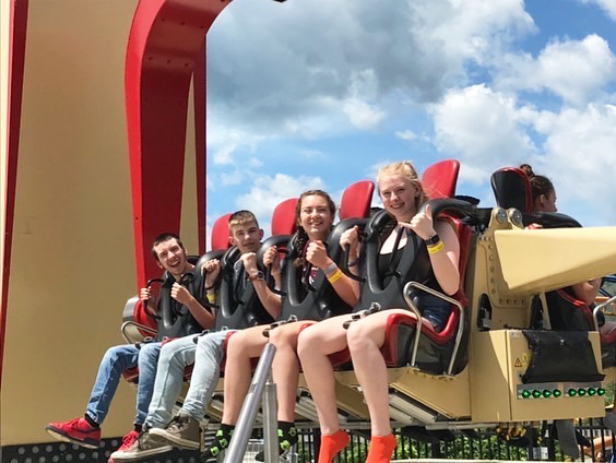 Four people are strapped in ready for an amusement park ride