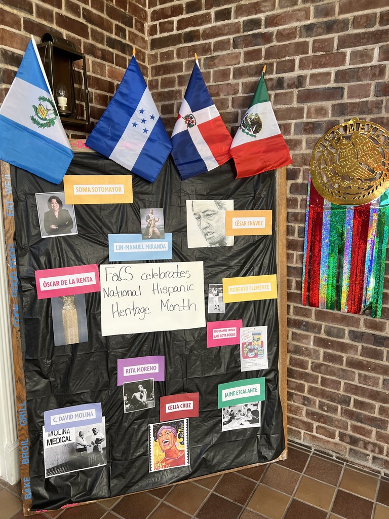 A bulletin board is decorated with Hispanic countries' flags and photos and names of well-know Hispanic American figures.
