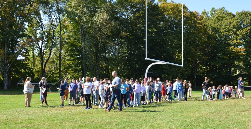 Students stand in lines surround the goal post on the football field.