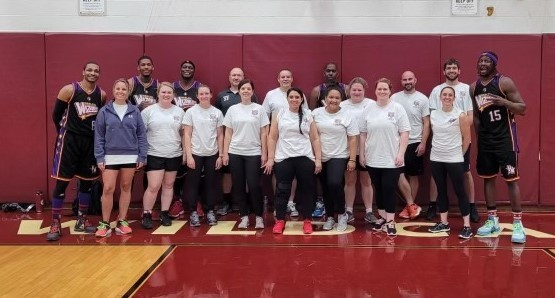 LMCS staff pose for a photo with the Harlem Wizards in the LMCS gym.