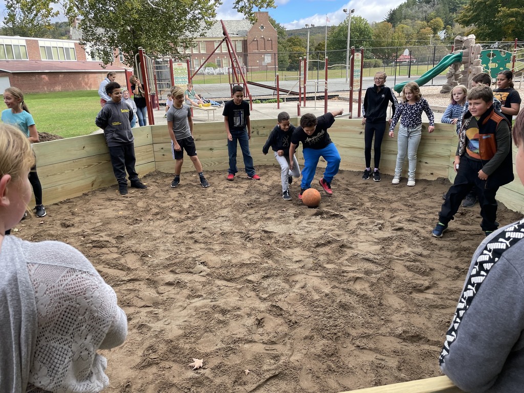 Two students go for a ball in a Gaga Ball pit as other students watch