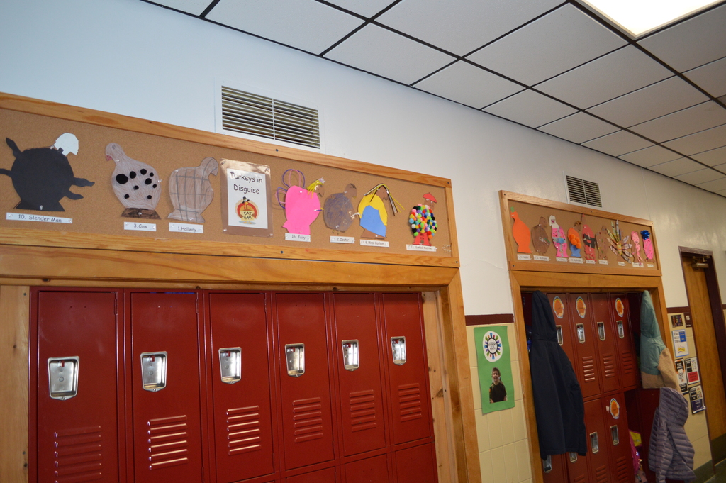 Drawings of disguised turnkey  line a bulletin board above lockers.