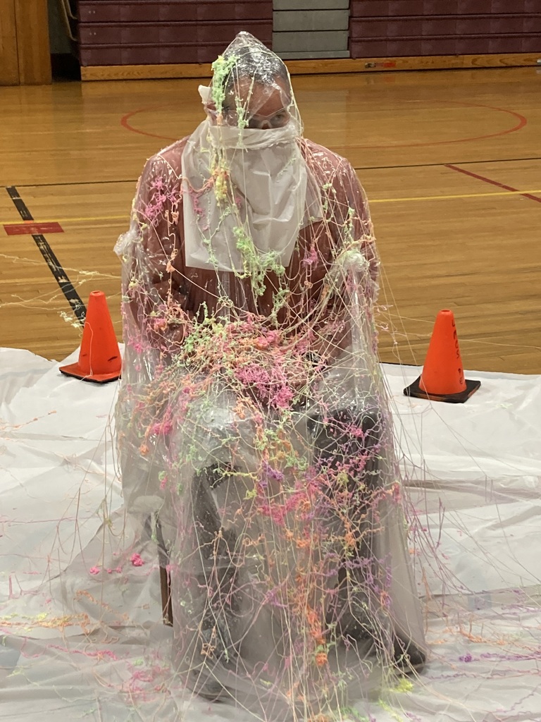 A person sits in a chair covered in silly string and plastic