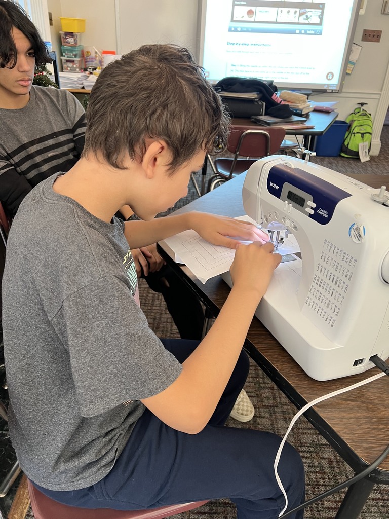  A student uses a sewing machine as another student watches