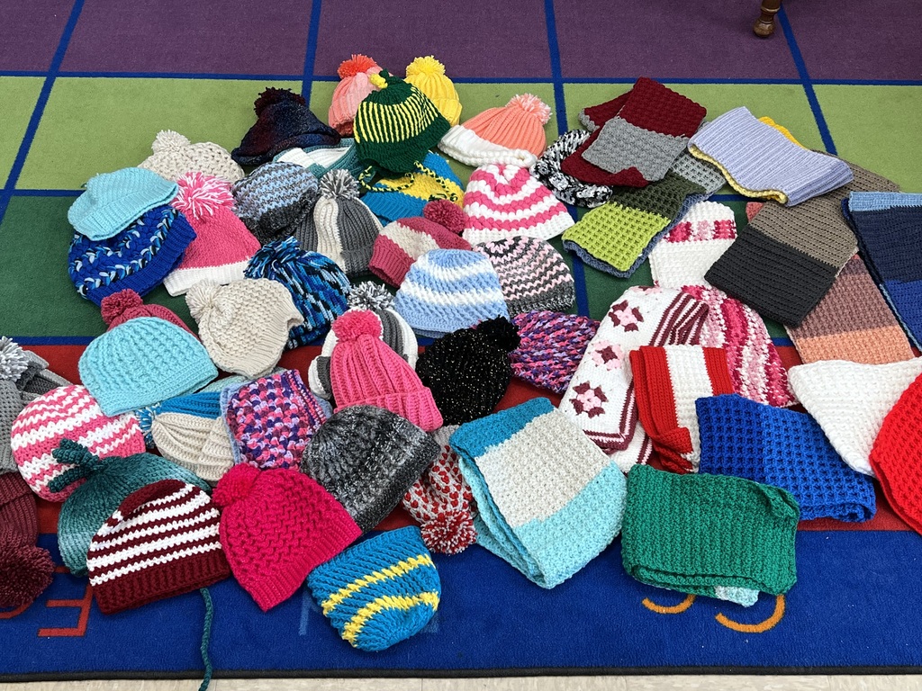 A pile of handmade hats scarves and mittens in a pile 