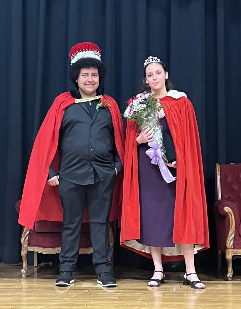 A couple dressed in red capes and crowns