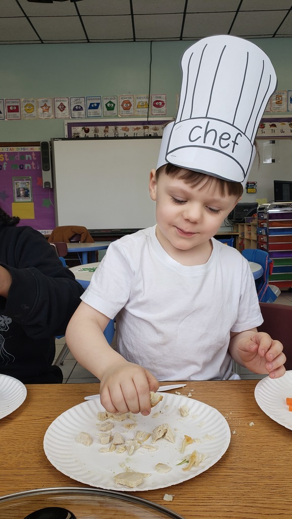 A student in a chef's hat breaks up ingredients for soup