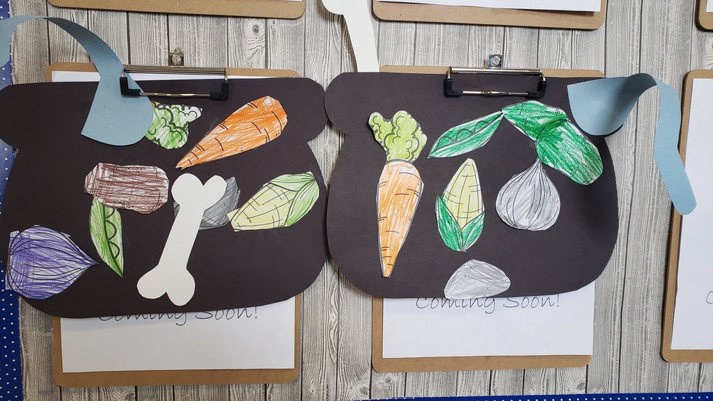 drawings of soup ingredients are placed on black paper and placed on a clipboard