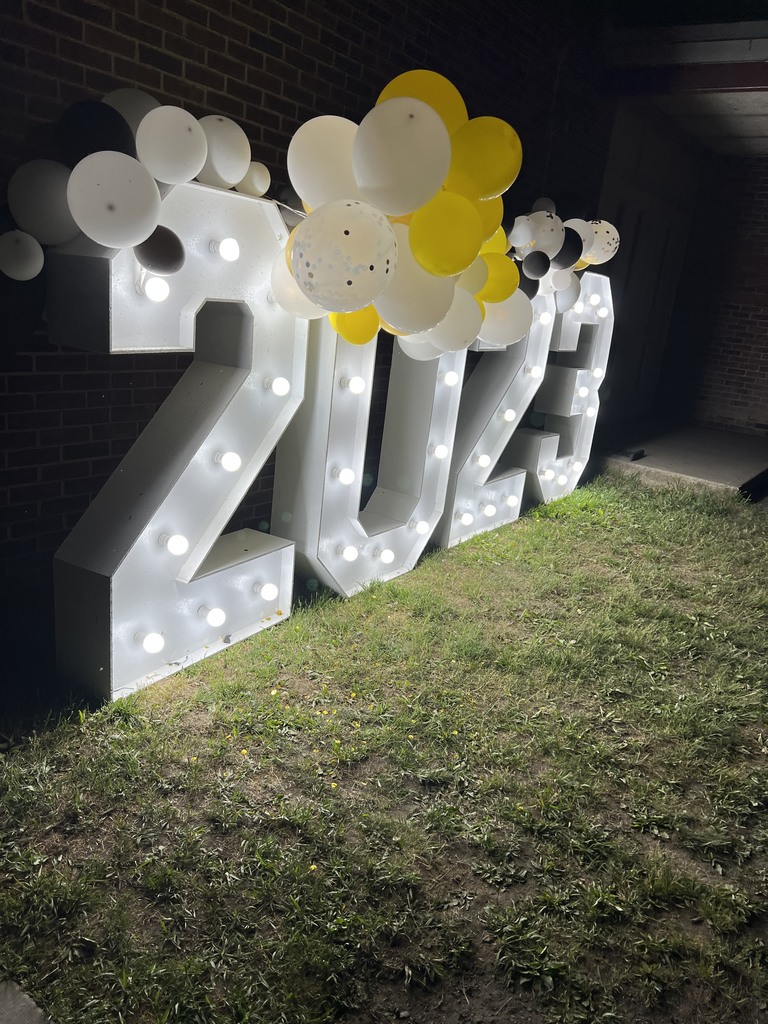 A lighted 2023 sign with yellow and white balloons