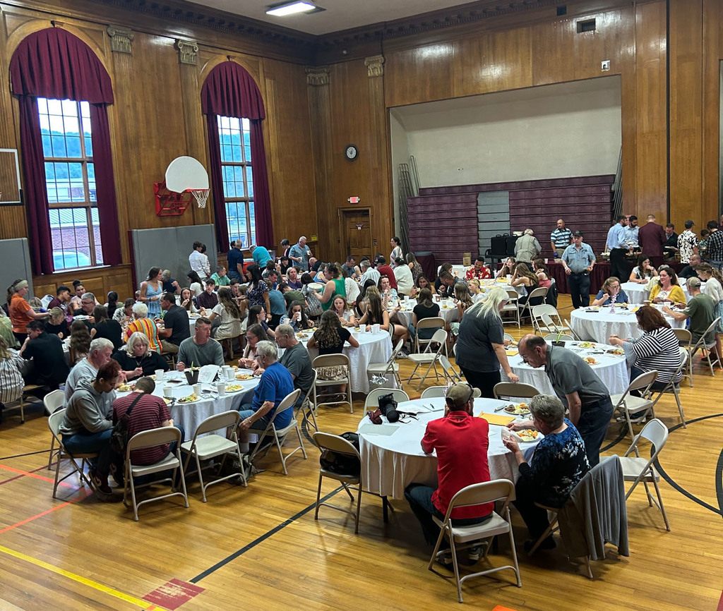 People sit at round tables in a gymnasium