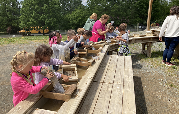 Students sift dirt in a sluice