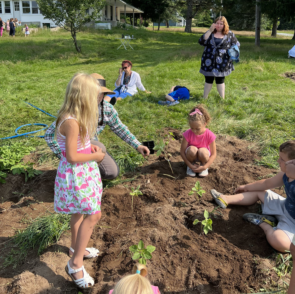 Students plant in a mound of dirt.