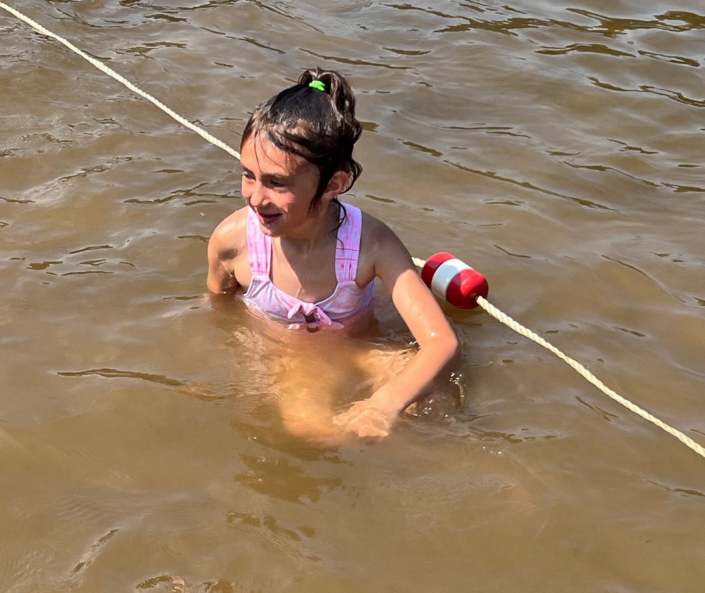 A student sits in the water near a buoy line