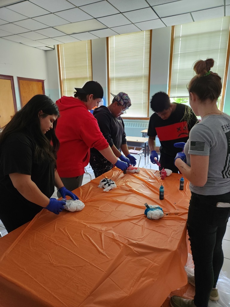 Students apply die to T-shirts at a table covered in an orange cloth