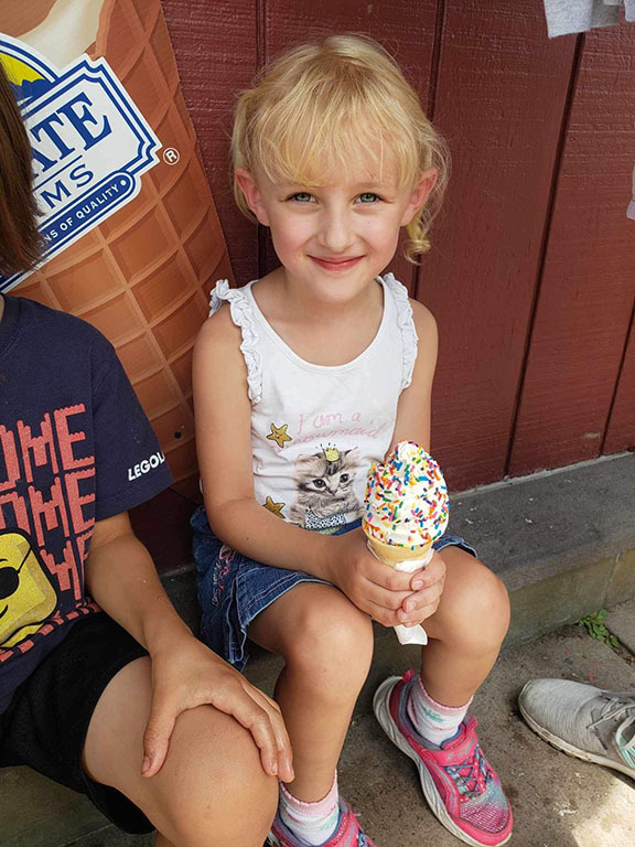 A girl smiles holding an ice cream cone