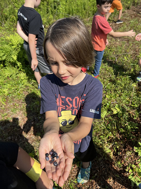 A student holds blueberries as other students are shown in the background