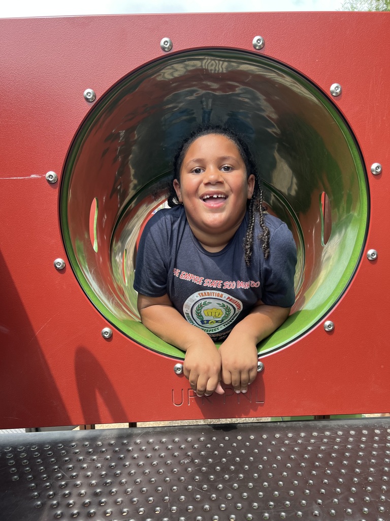 A student smiles looking out from a playground tube