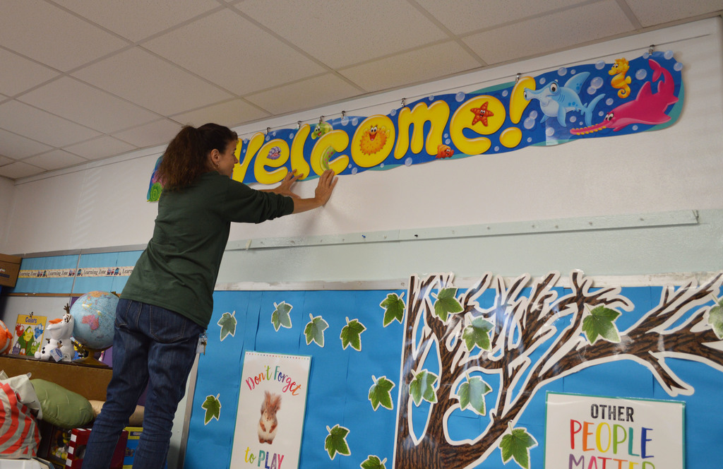 A teacher straightens a welcome sign on the wall