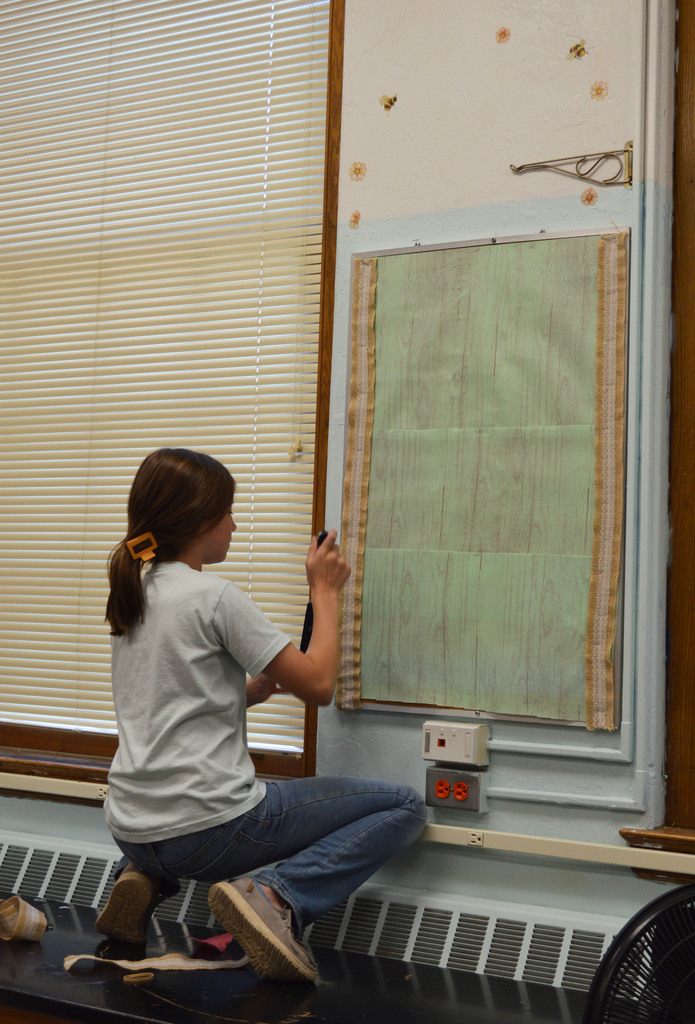 A student staples a border to a bulletin board