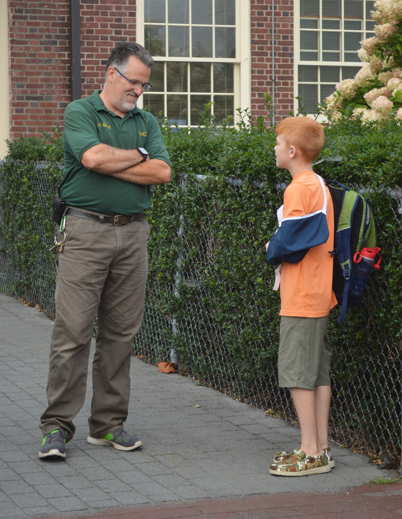 An adult talks to a student whose arm is in a sling