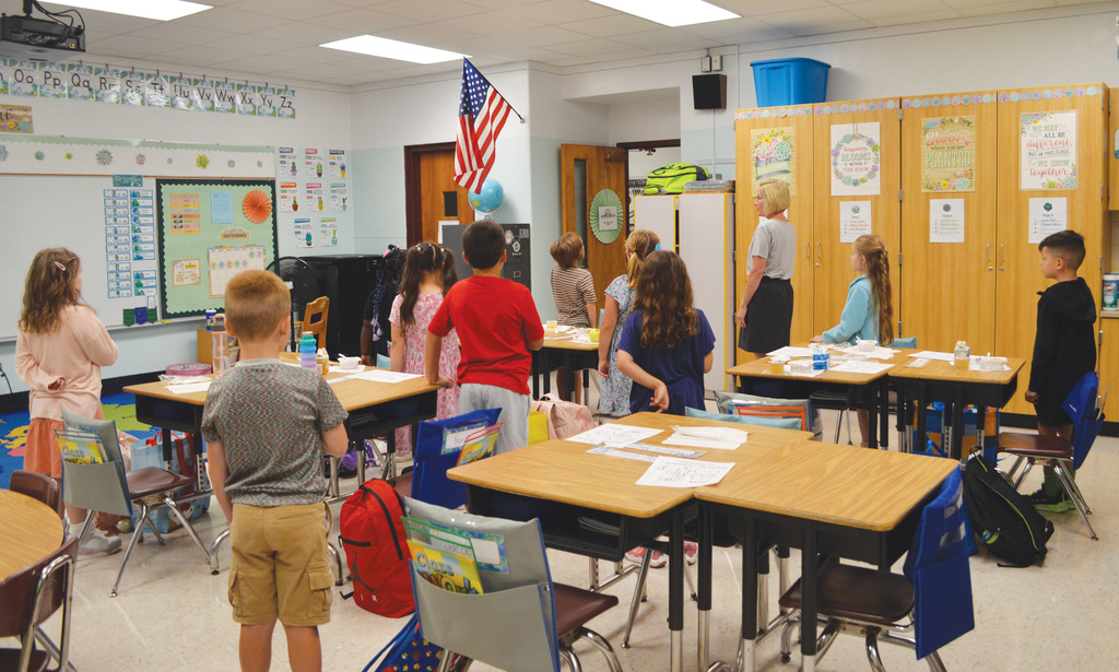 A teacher and students stand for the pledge of allegiance