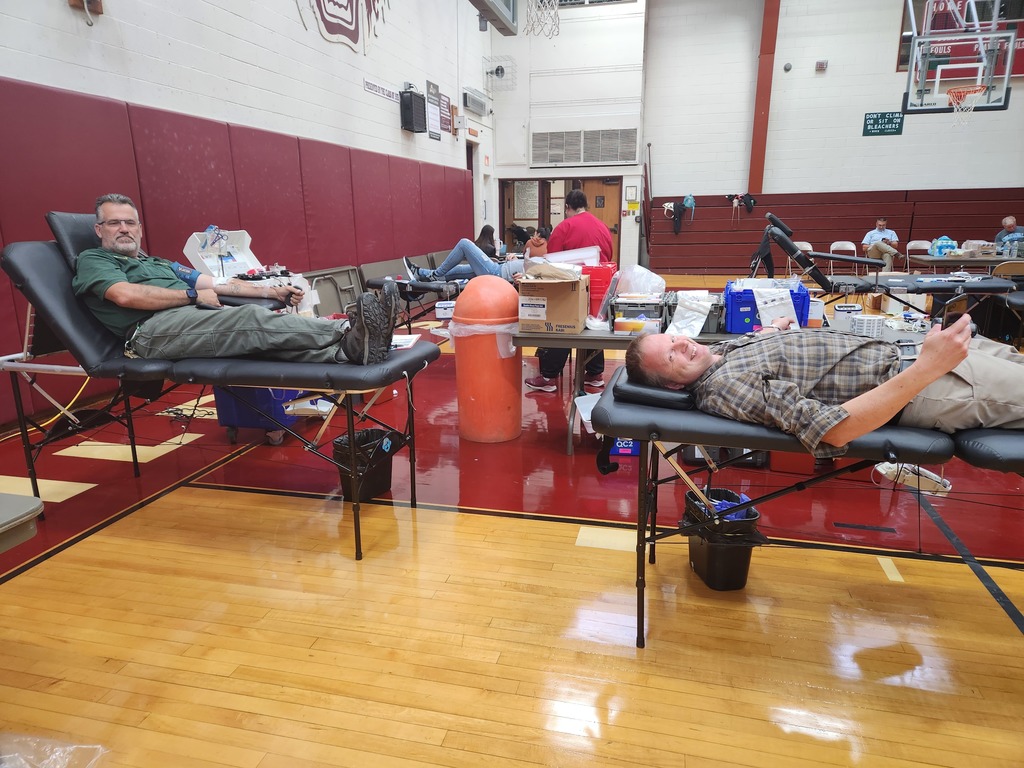 Two people lay on cots while giving blood